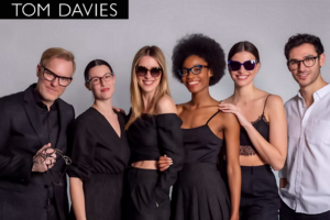 Tom Davies posing with several models, all showcasing his exclusive handcrafted eyewear designs, highlighting luxury, individuality, and bespoke craftsmanship, and Wittman Vision has 50 selections to choose from.